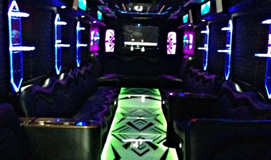 Party bus interior with neon green and purple lighting, black leather seating, and a nightclub-style atmosphere.