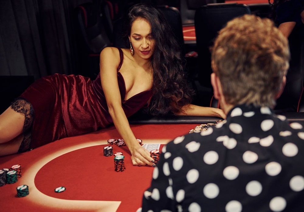 Sexy poker dealer in a red dress posing on a poker table.