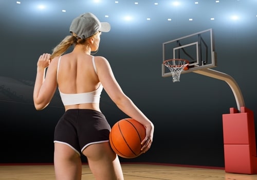 Young woman in revealing black shorts and a white crop top, holding a basketball with her back to the viewer.