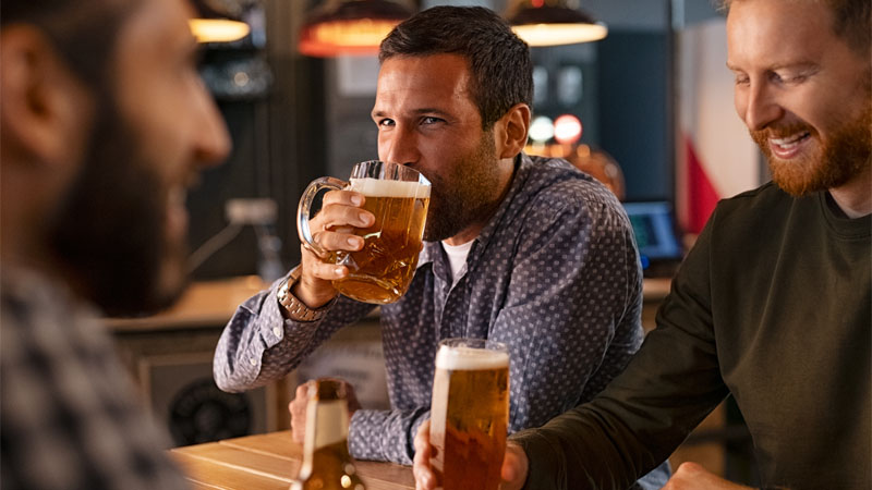Three men enjoying draft beer and chatting in a warm, inviting Palm Springs brewery.
