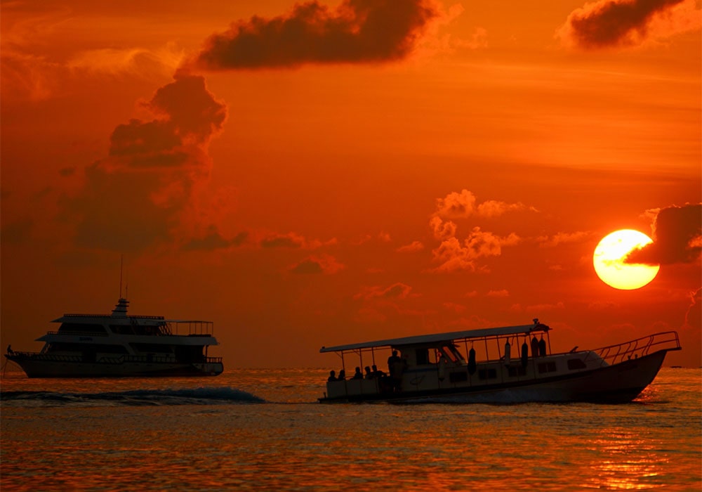 Sunset cruise with two boats silhouetted against the glowing orange sky.